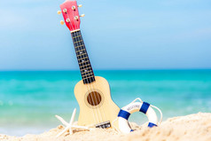 夏日的吉他在美丽的沙滩和蓝天的背景, 复制空间的放松。旅行和夏天概念