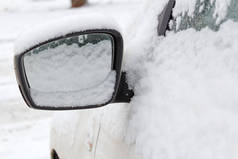 白雪覆盖的侧面镜子的汽车特写。冬季汽车