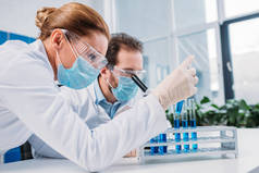 研究人员在白色大衣和医疗口罩一起使用试剂在实验室
