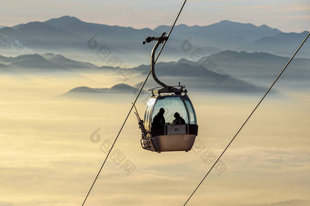 滑雪升降机电缆亭或汽车, 索道和索道运输系统为滑雪者与雾在谷背景