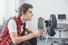青少年男孩玩视频游戏与手柄在家里