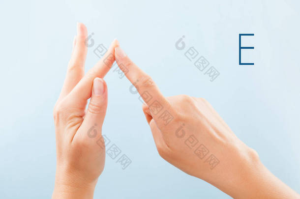 Fingerspelling 字母表。女性的手在蓝色背景显示聋静音 Bsl 字母 E.