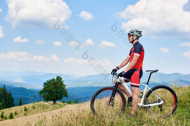 体育运动员站立与越野自行车在草的谷和享受夏天的山的<strong>秀</strong>丽风景, 健康<strong>生活</strong>方式和户外体育概念