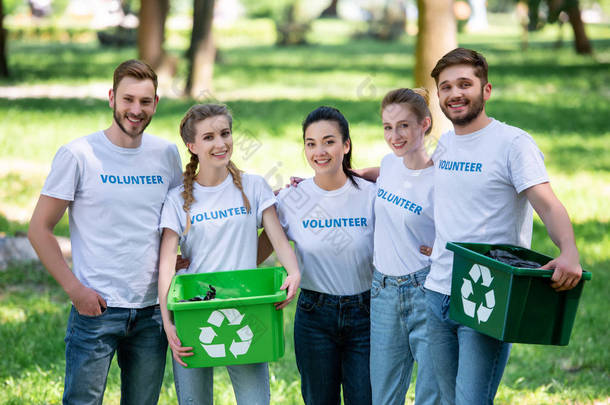 青年志愿者绿色回收箱的垃圾站在公园