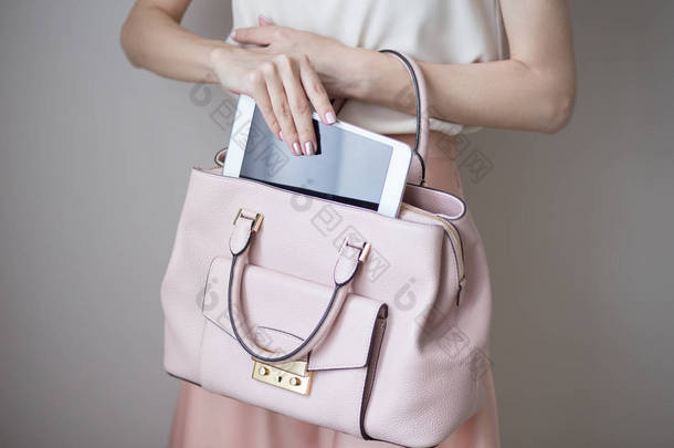 数字电子片在女人的手上。皮革浅粉色手袋, 夏季典雅风格
