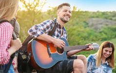年轻人用背包弹吉他给他在旷野的朋友。野营季节