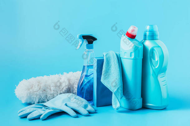 在蓝色背景下关闭除尘器、橡胶手套、清洗液、洗衣粉、抹布和洗衣液的全景图