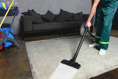 清洗白色地毯时使用吸尘器的人的裁剪照片