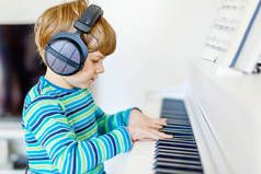 可爱的健康小男孩在客厅或音乐学校弹钢琴。学龄前儿童学习演奏乐器的乐趣。教育、技能概念
