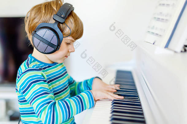 可爱的健康小男孩在客厅或<strong>音乐学校</strong>弹钢琴。学龄前儿童学习演奏乐器的乐趣。教育、技能概念