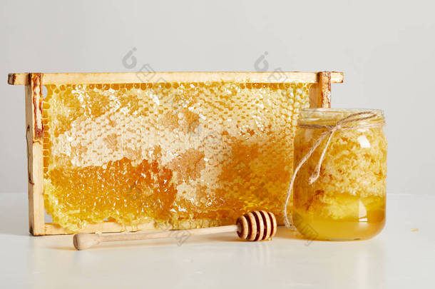 仔细查看木蜂蜜更深, 玻璃罐子与蜂蜜和堆蜂蜡在白色桌面上