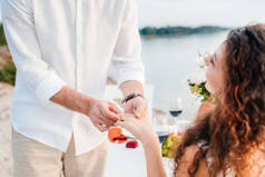 女人手指上的男人戴戒指在浪漫约会后的裁剪视图