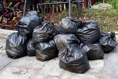废弃的塑料, 大量堆积如山的垃圾黑袋堆叠在地面公共公园, 许多倾倒黑色垃圾袋堆栈