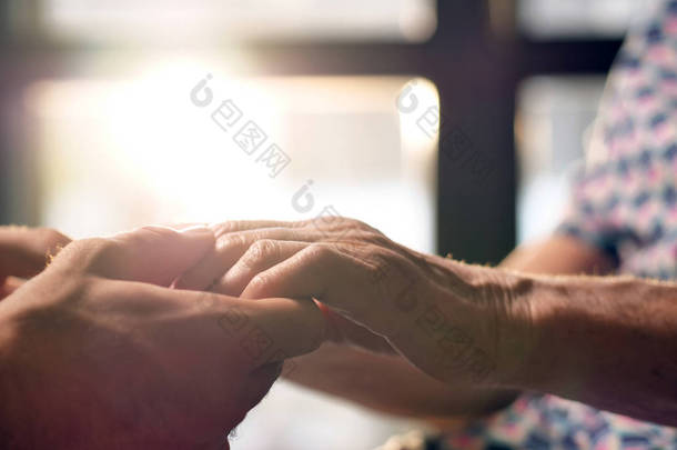 年轻人帮助她的祖母站起来, 牵着她的手。老年人支持和退休帮助的概念。帮助有需要的人