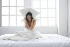 年轻的白种女人用枕头遮住头和耳朵.