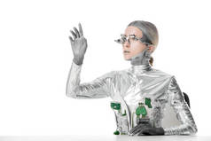 银色机器人坐在桌子上, 触摸一些孤立的白色, 未来的技术概念