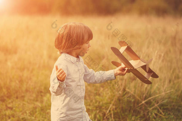 儿<strong>童</strong>飞行员飞行员与飞机在日落时, 小男孩玩纸板玩具飞机在户外, 在夏天的天空背景下。复古的调子。旅行的<strong>梦</strong>想