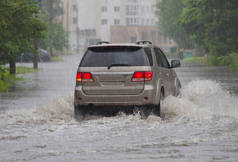 在洪水泛滥的道路上，汽车在大雨中行驶