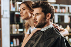 英俊的年轻人和美丽的女性发型师在美容院看