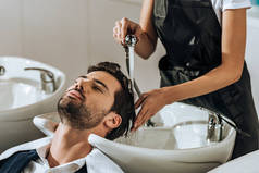 剪断的发型师洗头英俊的年轻人在美容院