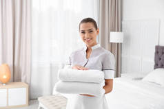 年轻的女服务员与干净的毛巾在卧室