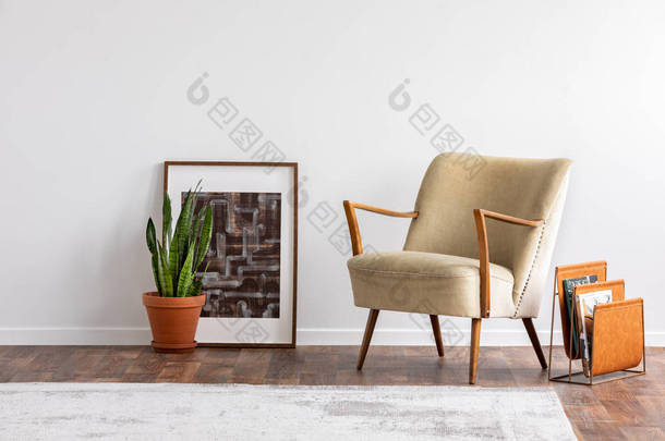 抽象图形在木框架旁边的绿色植物在陶瓷锅和<strong>优雅</strong>的米色扶手椅和<strong>橙色</strong>杂志架, 真实的照片