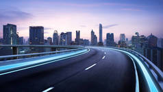 弯弯曲曲的天桥高速公路前进的道路与曼谷城市景观夜景。运动模糊效果适用