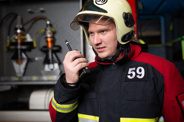 戴着头盔的男性消防队员在电台讲话的照片
