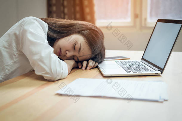 商务妇女在上班的时候累得睡在办公室里。由于加班时间长.