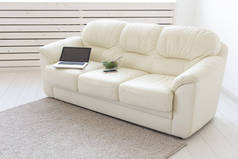 商务和室内概念----可以看到带沙发的白色客厅、一台开放式笔记本电脑、家庭内饰