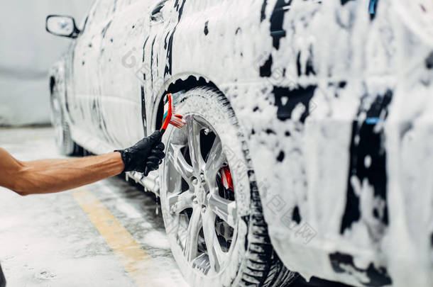 洗车服务, 汽车泡沫, 侧视图。汽车细节, 用刷子清洗车轮
