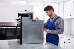 Kitchen用数字万用表修理烤箱的年轻男性修理工