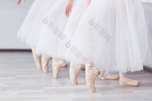 脚在尖。芭蕾学校的练习。芭蕾课。一群女孩站在一排, 伸出双腿, 在尖上滑行。孩子们穿着白色裙子。老师领导一个舞蹈课.