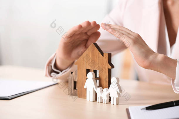 女性<strong>代理</strong>覆盖木结构房屋和家庭在桌子上, 特写镜头。家庭保险