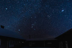 星光灿烂的天空和在冬天的夜晚被雪覆盖的房屋
