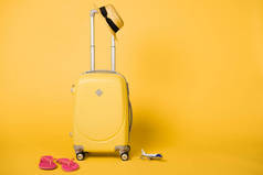 明亮的黄色旅行袋, 草帽, 粉红色翻盖和平面模型在黄色背景
