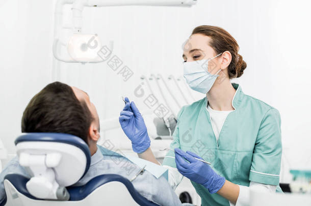<strong>女性</strong>牙医在面具<strong>拿</strong>牙仪器接近患者在牙科诊所