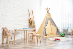 舒适的儿童房内部有桌子、凳子和帐篷