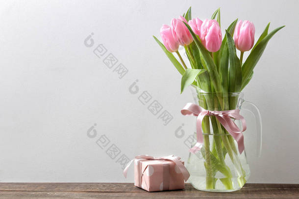 美丽的粉<strong>红色</strong>郁金香花花束在花瓶和<strong>礼品</strong>盒在灰色的墙壁<strong>背景</strong>。文本的位置。春天。假期.