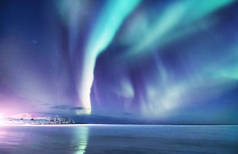 挪威洛福敦群岛上的北极光。夜晚的天空与极光。夜间冬季景观与极光和反射的水面上。挪威的自然背景