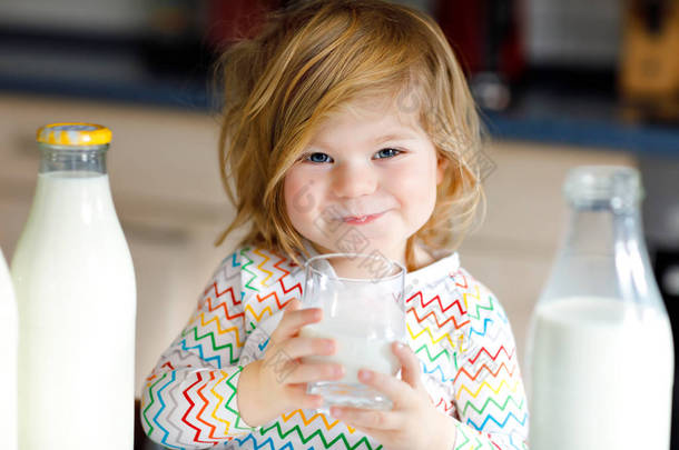 可爱的蹒跚学步的小女孩早餐喝<strong>牛奶</strong>.可爱的女婴，有很多瓶子。以<strong>牛奶</strong>为健康<strong>钙</strong>来源的健康儿童。早上在家或托儿所里的小孩.