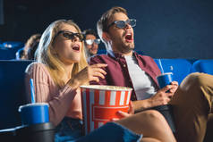 震惊的情侣在3d 眼镜与爆米花一起看电影在电影院