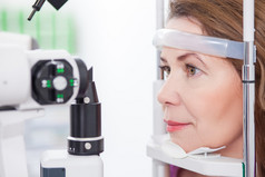 Mature lady is looking into eye test machine