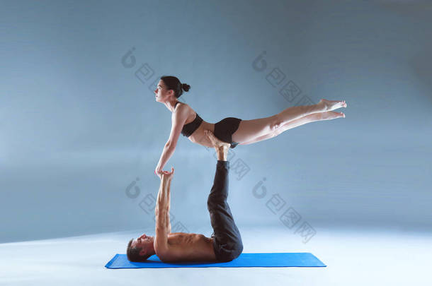 年轻夫妇一起练习杂技<strong>瑜伽</strong>工作室在<strong>垫</strong>子上。杂技。几个<strong>瑜伽</strong>。双人<strong>瑜伽</strong>.