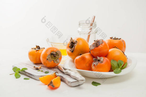 一堆成熟的柿子在一张白色桌子上的碗里