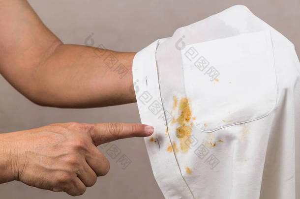 人指着洒在白色衬衣上的咖喱污渍.