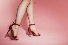 女性腿的裁剪的图片在时尚高跟鞋在粉红色背景