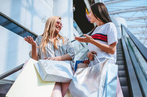 两个有魅力的年轻女孩在现代购物中心购物购物袋.