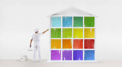 画家人的后方看法指向用手指颜色房子模型在墙壁上, 与油漆滚筒和桶, 被隔绝在白色