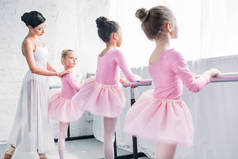 可爱的小孩子穿着短裙裙在芭蕾舞学校与老师练习